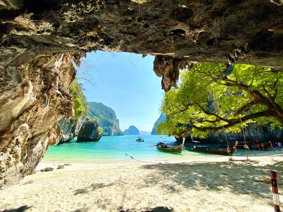 Longtail boats moored at Hong Island framed by a limestone cave